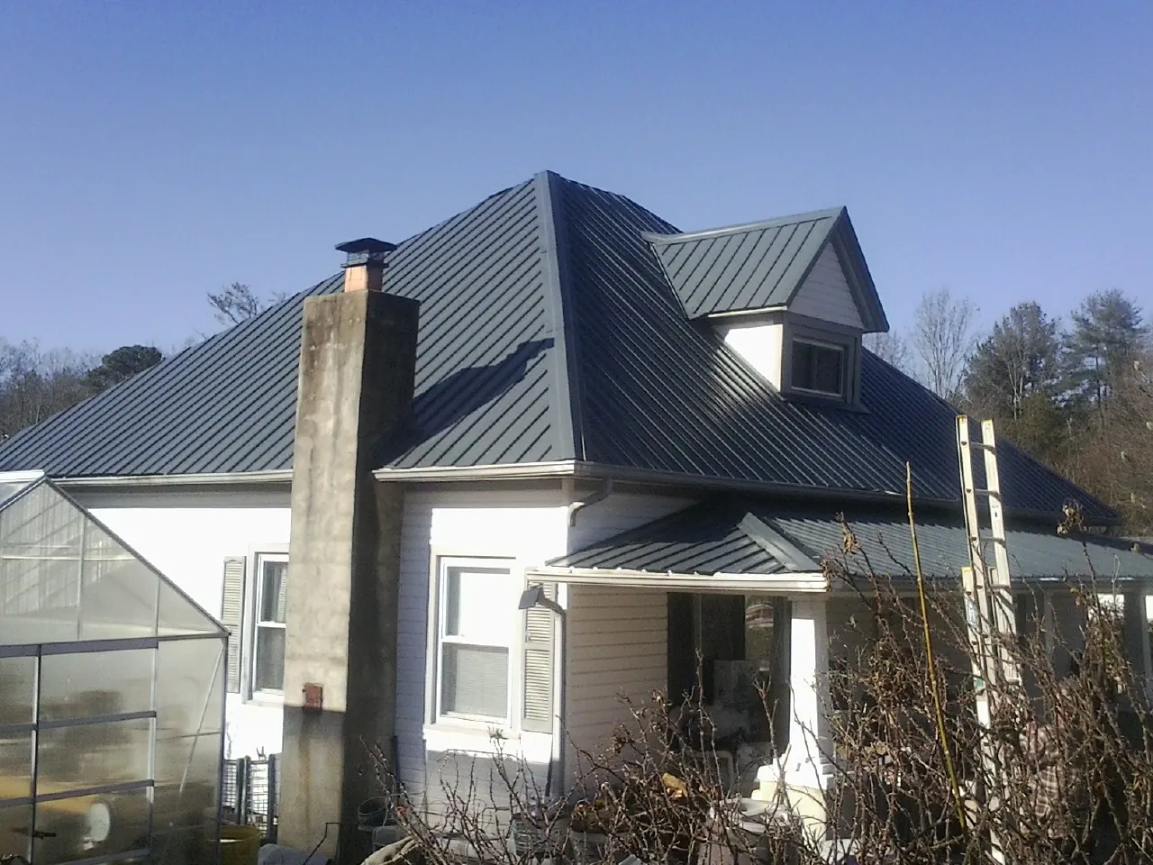 Dark blue standing seam metal roof on a white farmhouse with dormer — Slate & Tile Roof Repair by Roofing Brothers in Fort Hood
