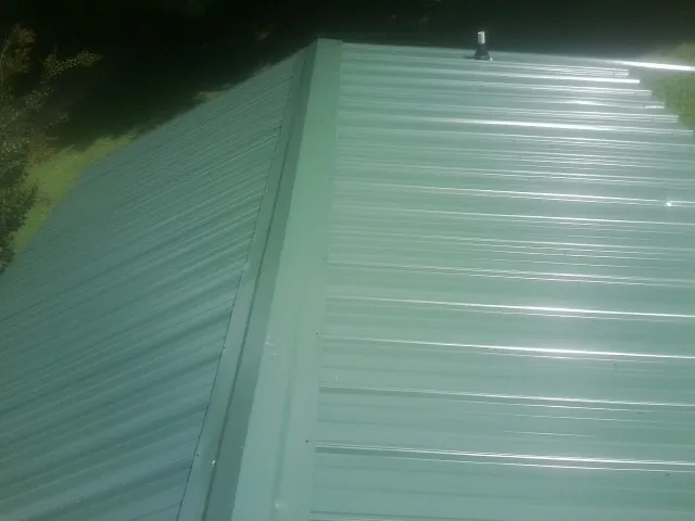 New green metal panels meeting at the ridge of a roof — Flat Roof Repair work by our crew in Fort Hood