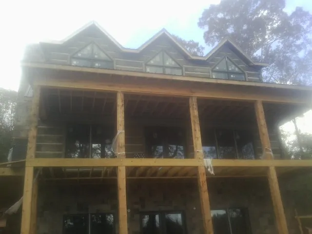 Dormers and porch framing on a large log home under construction — Roof Coating work by our crew in Fort Hood
