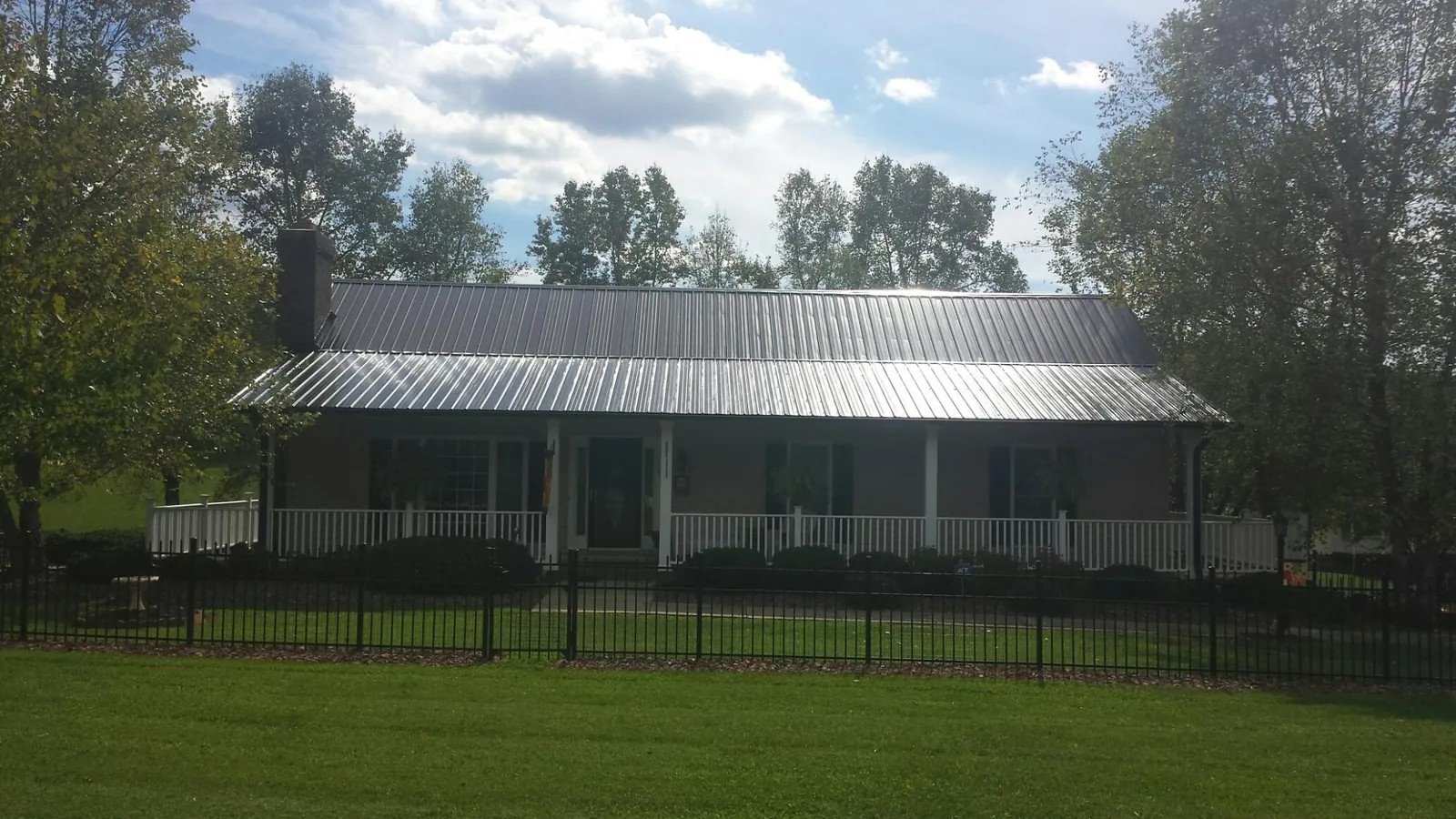 Gray metal roof on a brick ranch with a full width front porch — Gutter Guard Installation work by our crew in Fort Hood