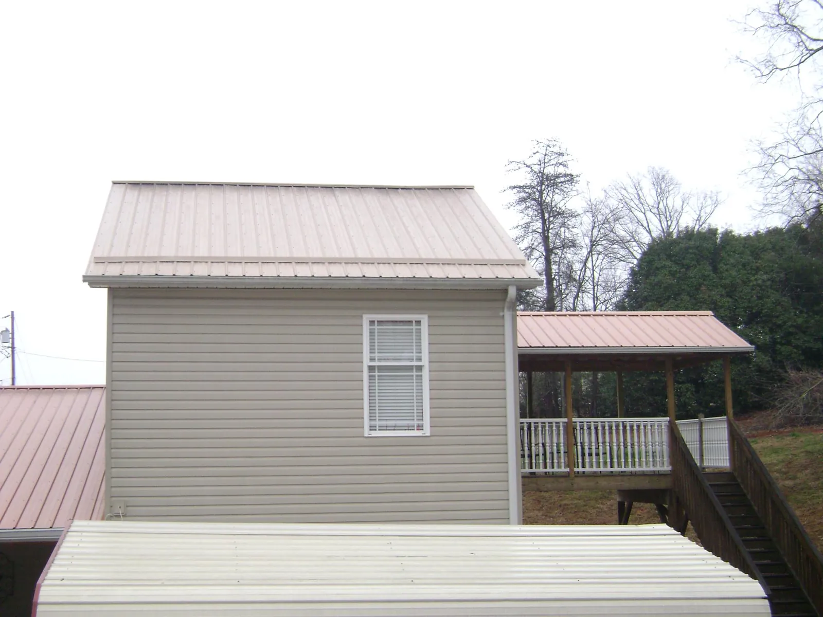 Tan metal roofs on a two story addition and attached porch, from a Roof Replacement job in Fort Hood